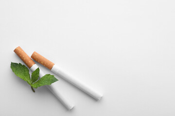 Menthol cigarettes and fresh mint leaves on white background, flat lay. Space for text