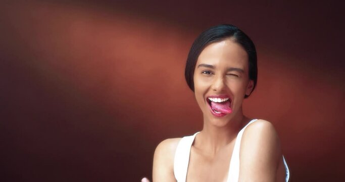 Portrait of beautiful young female model standing alone and posing at camera and having fun showing tongue.
