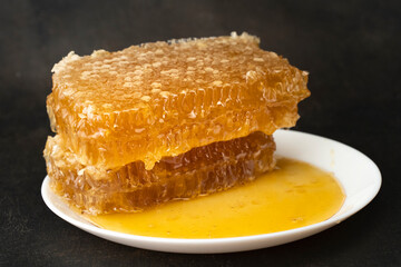 Honeycombs in Liquid Organic Honey Close Up. Golden fresh honey is pouring. Harvest beekeeping. Honey Dripping to Honey Dipper. Concept of healthy food and sweet meals
