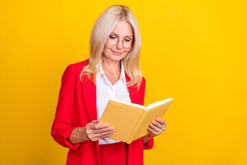 Photo of attractive mature woman read book hobby novel learning isolated over yellow color background
