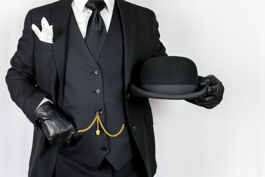 Portrait of Man in Dark Suit Holding Bowler Hat on White Background. Vintage Style and Retro Fashion of Classic English Gentleman.