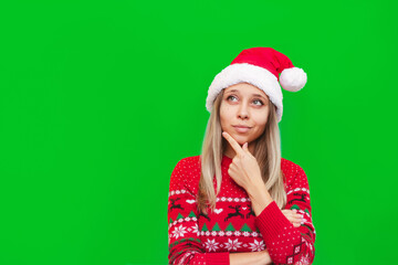 A young thoughtful blonde woman in a Christmas red deer warm sweater and a Santa's hat thinks about...
