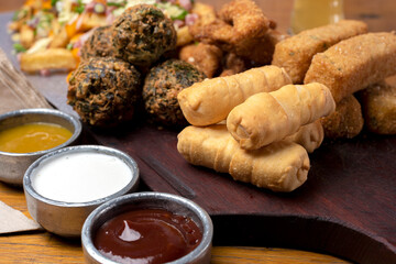 picada table with tequeños chicken sticks vegetable croquettes with assorted sauces beer and french fries