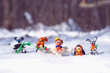 Figurines of fairy-tale characters in the winter forest. An angel with a gift, a dwarf, a rabbit...