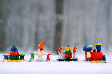 Toy train with Christmas figures on the background of snow.