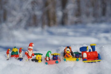 Toy train with fairy-tale characters and gifts in the winter forest. Gnome, Santa Claus, penguin...