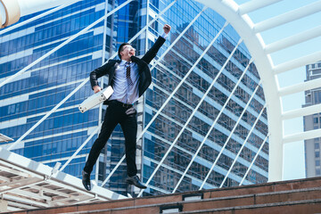 Successful businessman celebrating his victory with jump up in feeling happy on cityscape background.