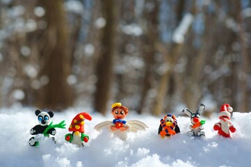 Figurines of fairy-tale characters in the winter forest. An angel with a gift, a dwarf, a rabbit...