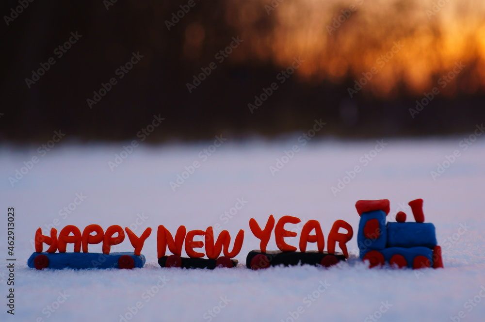 Poster A toy train and a happy new year sign on the background of the sunset.