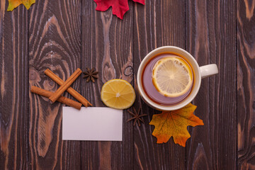 A cup of tea with lemon and cinnamon sticks on a wooden table, warm knitted snood. autumn mood