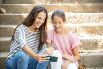 Happy girls watching memes on smartphone