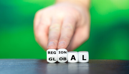 Hand turns dice and changes the word global to regional. - obrazy, fototapety, plakaty