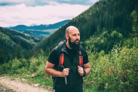 Hiking in the mountains. Handsome bearded man hiking mountains with heavy backpack travel wandering lifestyle adventure concept summer vacation outdoors alone in the wild.