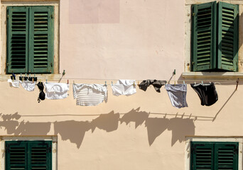 Laundry on the clothes line and old wall with green window shutters. Detail from Rovinj, Istria, Croatia