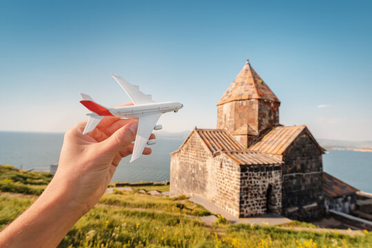 toy airplane on the background of a traditional Armenian ancient church and Sevan lake. Concept of air flight transportation and travel destinations