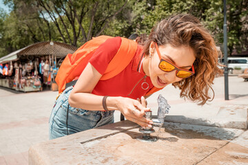 A woman drinks from a street fountain, which may contain contaminated and dangerous water for health.