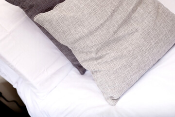 close up of grey and white cushions on bed