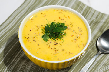 Plate of pumpkin cream soup with herbs.