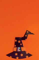 Black witch hat on an orange background. Halloween. Copy space. View from above.