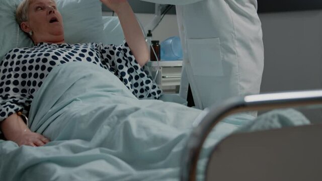 Medical team helping patient with respiratory disease, using oxygen tube mask against heavy breathing and stethoscope in hospital ward. Retired woman hyperventilating at intensive care