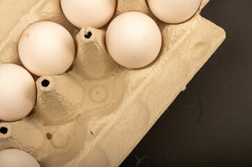 White chicken eggs in a tray made of white cardboard, close-up selective focus.
