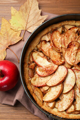 Delicious apple pie, fresh fruit and dry leaves on wooden table, flat lay