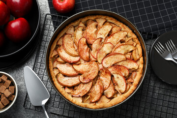Delicious apple pie and ingredients on grey table, flat lay