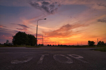 Zachód słońca i znak STOP na ulicy. - obrazy, fototapety, plakaty