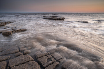 Rocky shoreline at Nash Point, Glamorgan, south Wales. Sunset over the shoreline, long exposure to smooth out the  movement in the sea. 