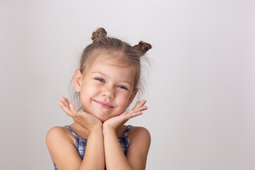 Portrait of caucasian cute little girl of five years old holdings head chin on hands on the white...