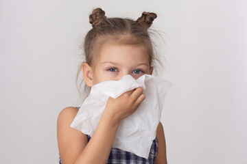 Portrait of caucasian cute little girl of five years old holdings napkin wiping nose by hand on the...