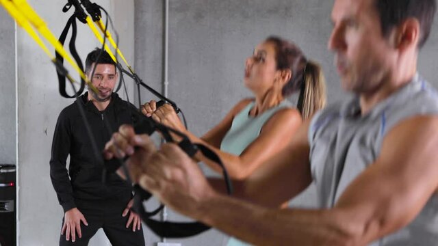 Man and woman do assisted squats with jumps at an indoor gym