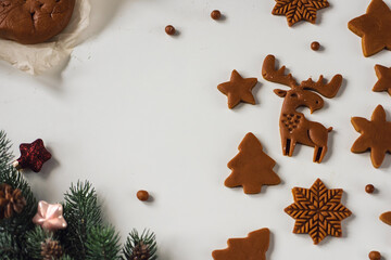 Many blanks of gingerbread cookies of different shapes on table with Christmas decor