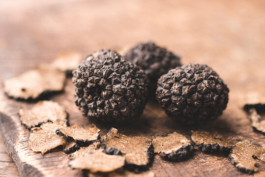 Black truffles on the old wooden table, rustic style, selective focus