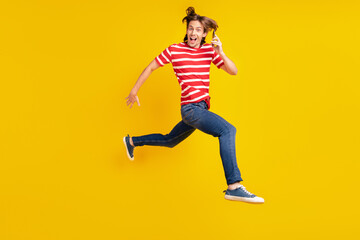 Fototapeta na wymiar Photo of pretty sweet young guy dressed red t-shirt running jumping modern gadget smiling isolated yellow color background