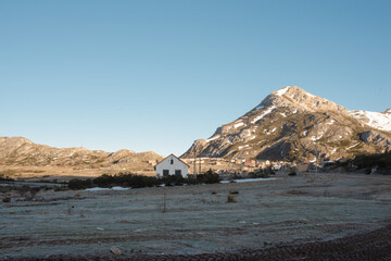 Casa blanca rodeada de montañas nevadas en el amanecer sobre un cielo azul y con las montañas de...