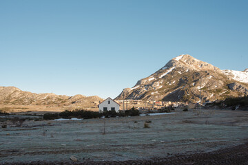 Casa blanca rodeada de montañas nevadas en el amanecer sobre un cielo azul y con las montañas de fondo.