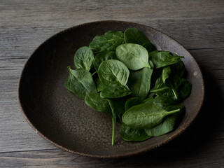 fresh spinach leaves on rustic plate on a wooden table. Healthy food concept.