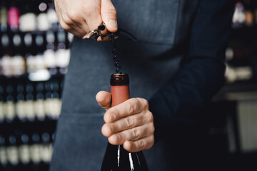 Sommelier opens cork of bottle of red wine with corkscrew