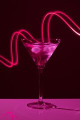 Martini glass with drink and ice against creative lighting