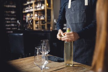Closeup hand of Sommelier opens cork of bottle of white wine with corkscrew