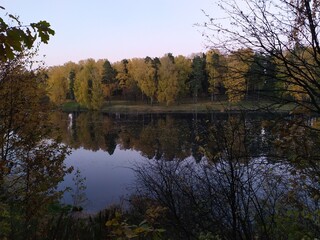 Fall landscape with reflection of trees in the calm river water in sunny autumn evening