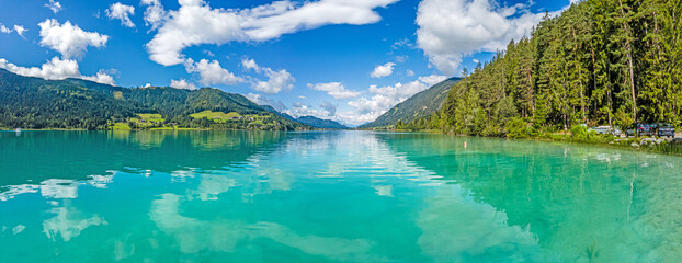Fototapeta na wymiar Panoramic view over turquoise lake Weissensee in Austrian province Carinthia during daytime