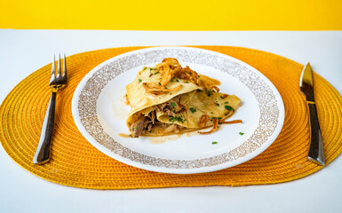Pancake with pulled pork meat and cabbage on plate.
