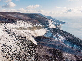 Mountains with snow in winter. Aerial view of canyon and Black sea
