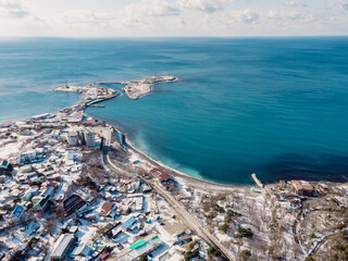 Drone view of coastline with sea and lighthouse on island in winter