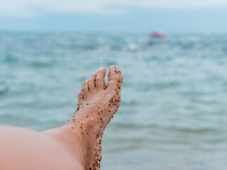 woman's foot looking at the sea full of sand
