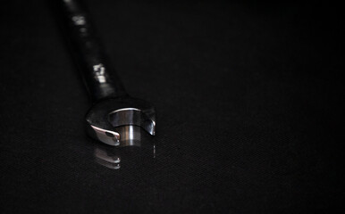 Wrench on shiny black surface. Universal professional tool for car repair. Low key photo. Free...