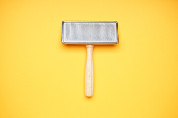 Grooming brush. Brush for dogs on a yellow background. Flat lay.