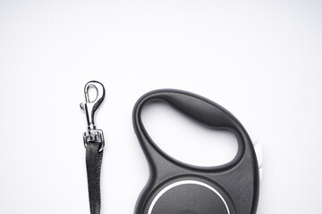 Black retractable dog leash on a white background, space for text, close-up, flat lay.